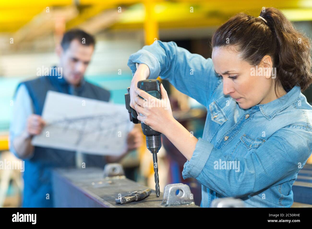 woman using drill with exertion Stock Photo