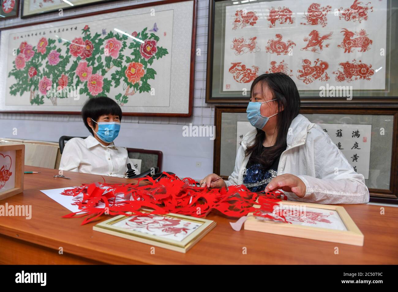 Changchun, China's Jilin Province. 29th June, 2020. Hua Li (L) guides trainee Wang Cong to make papercutting work in Jilin City, northeast China's Jilin Province, June 29, 2020. Hua Li became disabled due to illness when she was young. She decided to face up to the hardship and learned papercutting with the help of her family. In order to promote papercutting, Hua and her husband set up a papercutting workshop in Jilin which provides free papercutting training for disabled people. Credit: Zhang Nan/Xinhua/Alamy Live News Stock Photo