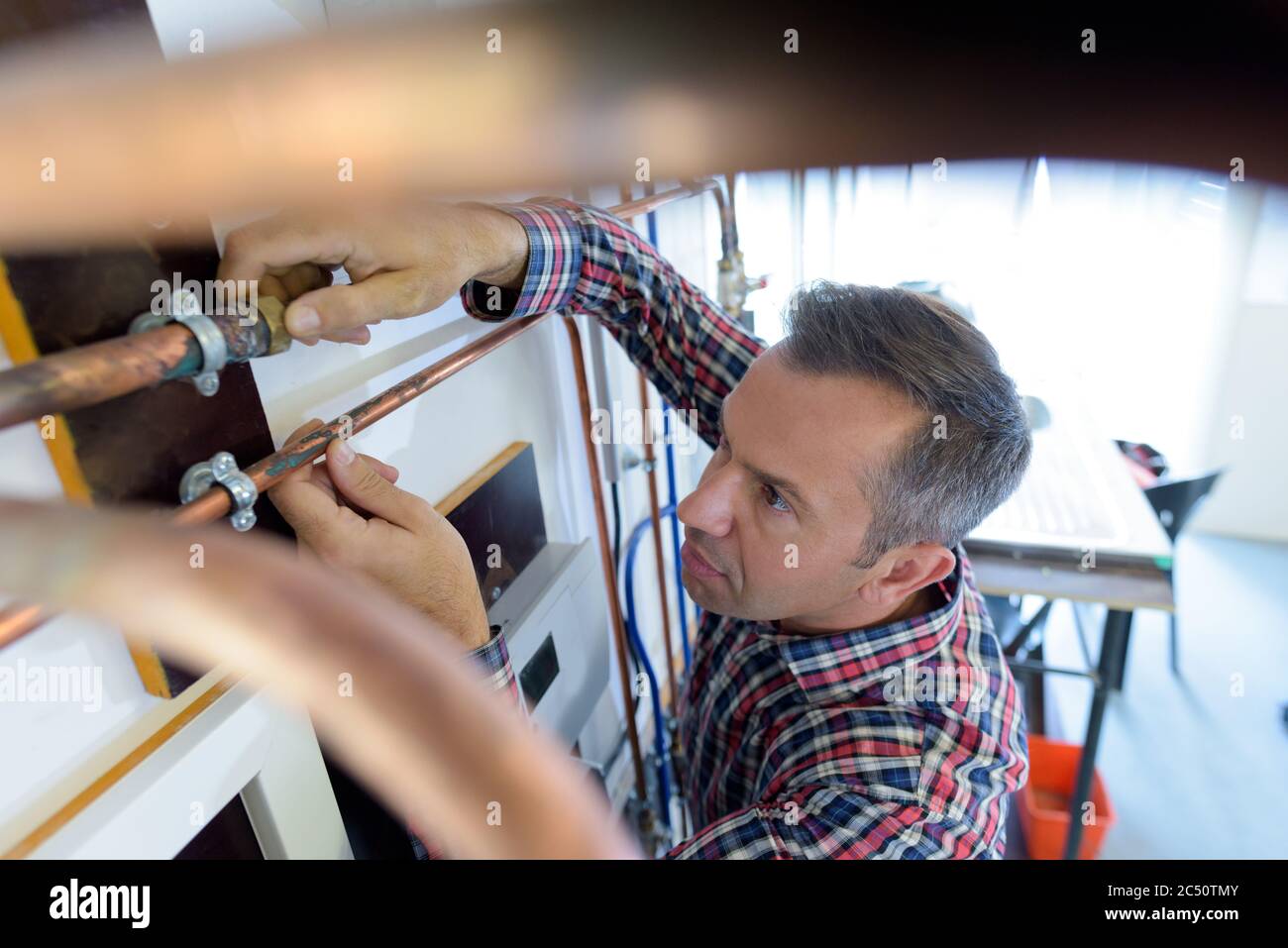 tradesman working on copper pipe installation Stock Photo