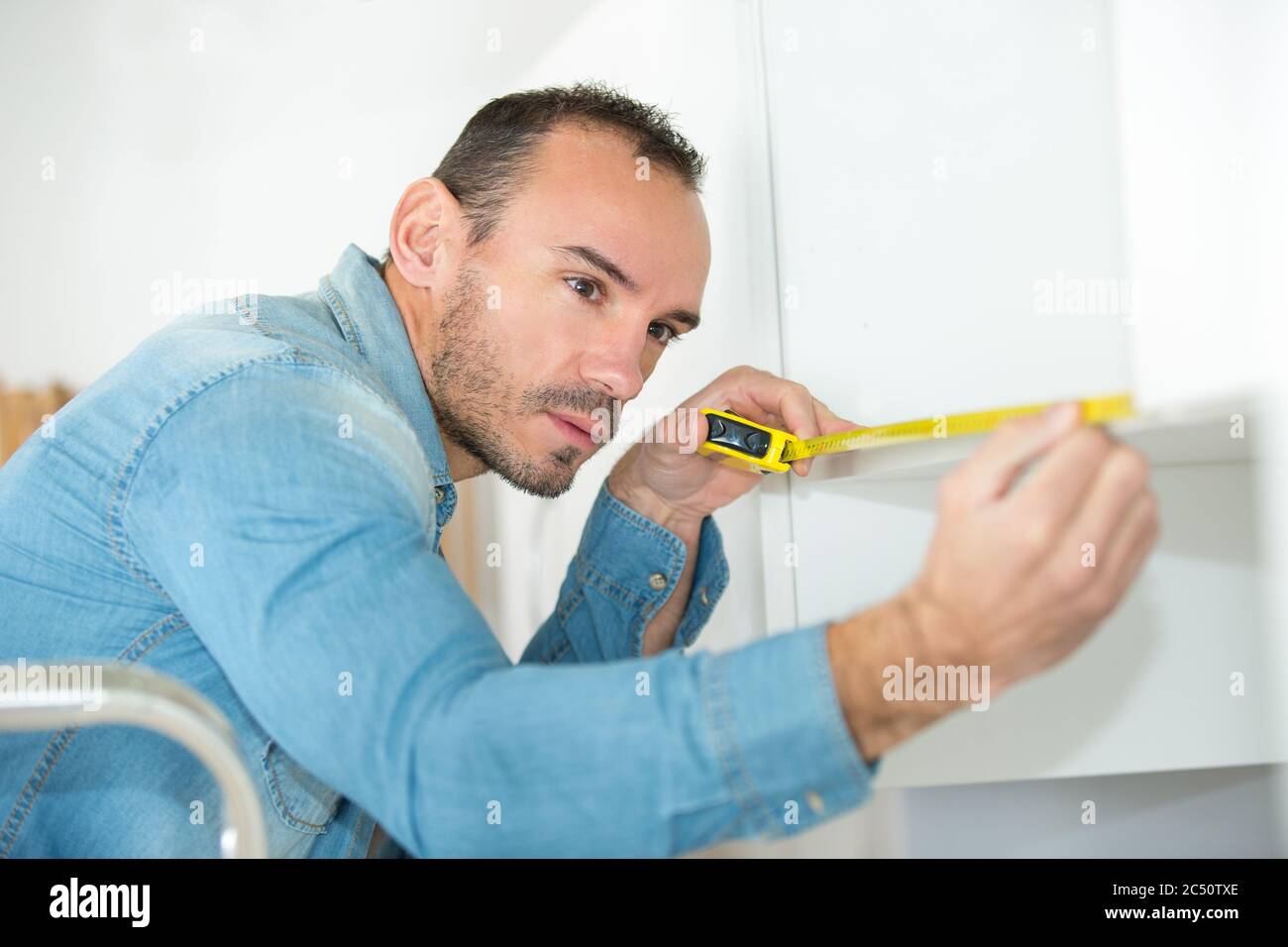a man measuring kitchen cupboard Stock Photo Alamy