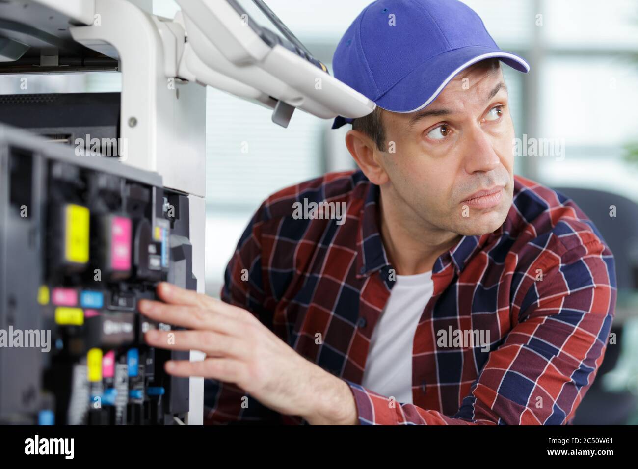 technician using a tablet to fix a printer Stock Photo