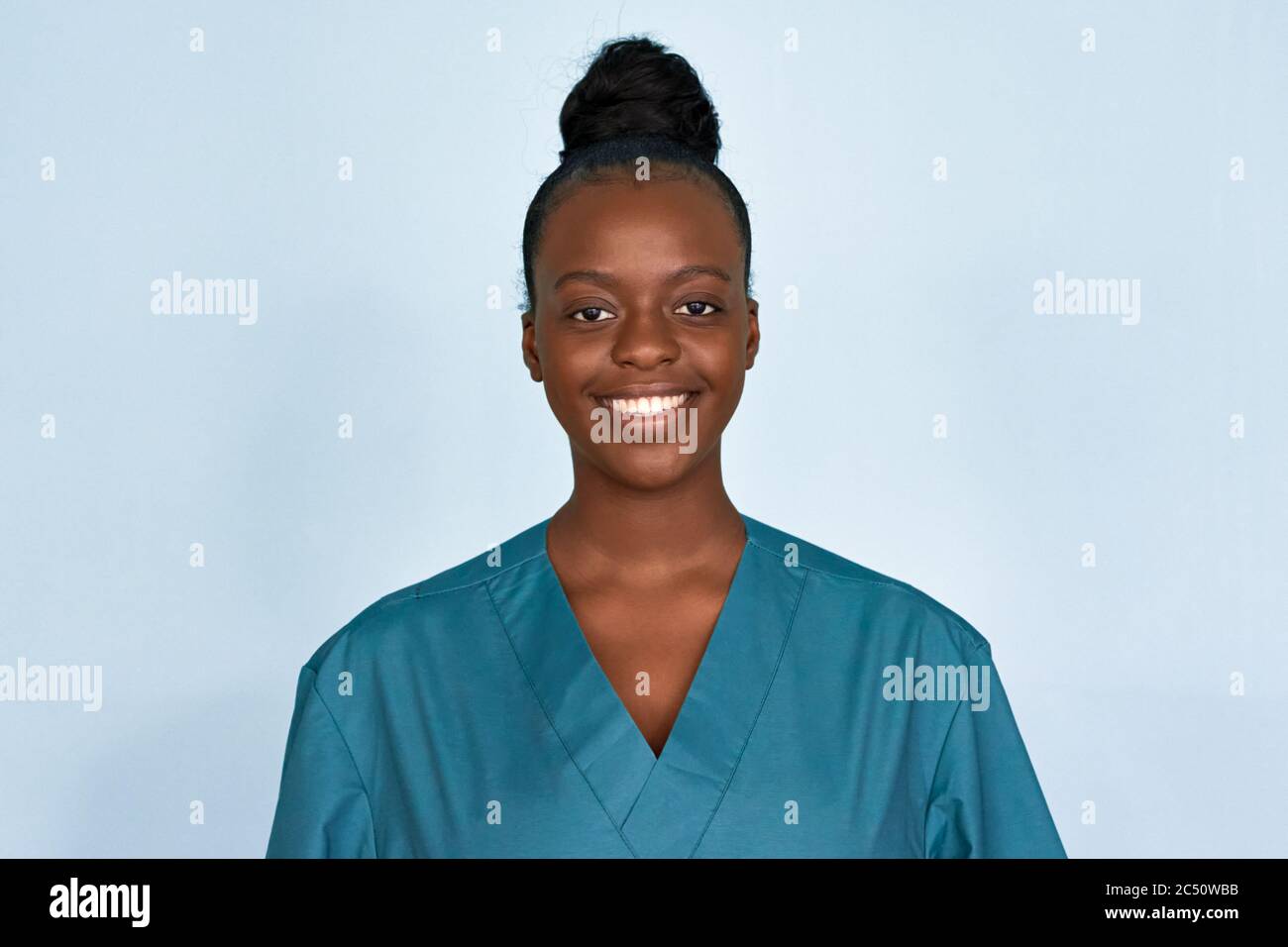 Happy young female african scrub nurse wear blue uniform isolated on background. Stock Photo
