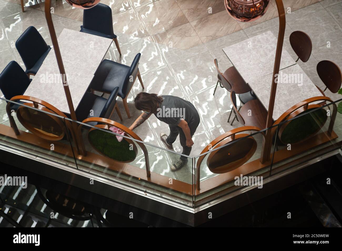25.06.2020, Singapore, Republic of Singapore, Asia - A staff member cleans the furnishing at a cafe inside the Marina Bay Sands shopping mall. Stock Photo