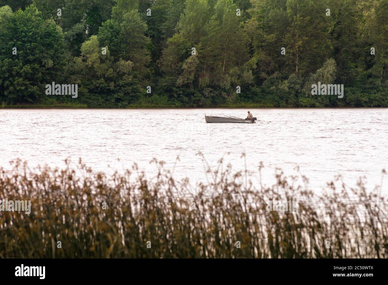 A fisherman on a boat on the Dnieper River in Kiev, Ukraine, between reeds and the forest Stock Photo