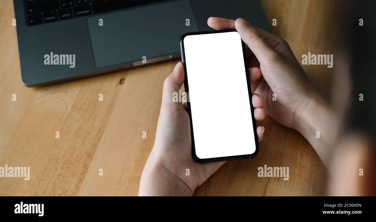 oman hand holding smartphone on workplace. Blank screen mobile phone for graphic display montage.. Stock Photo