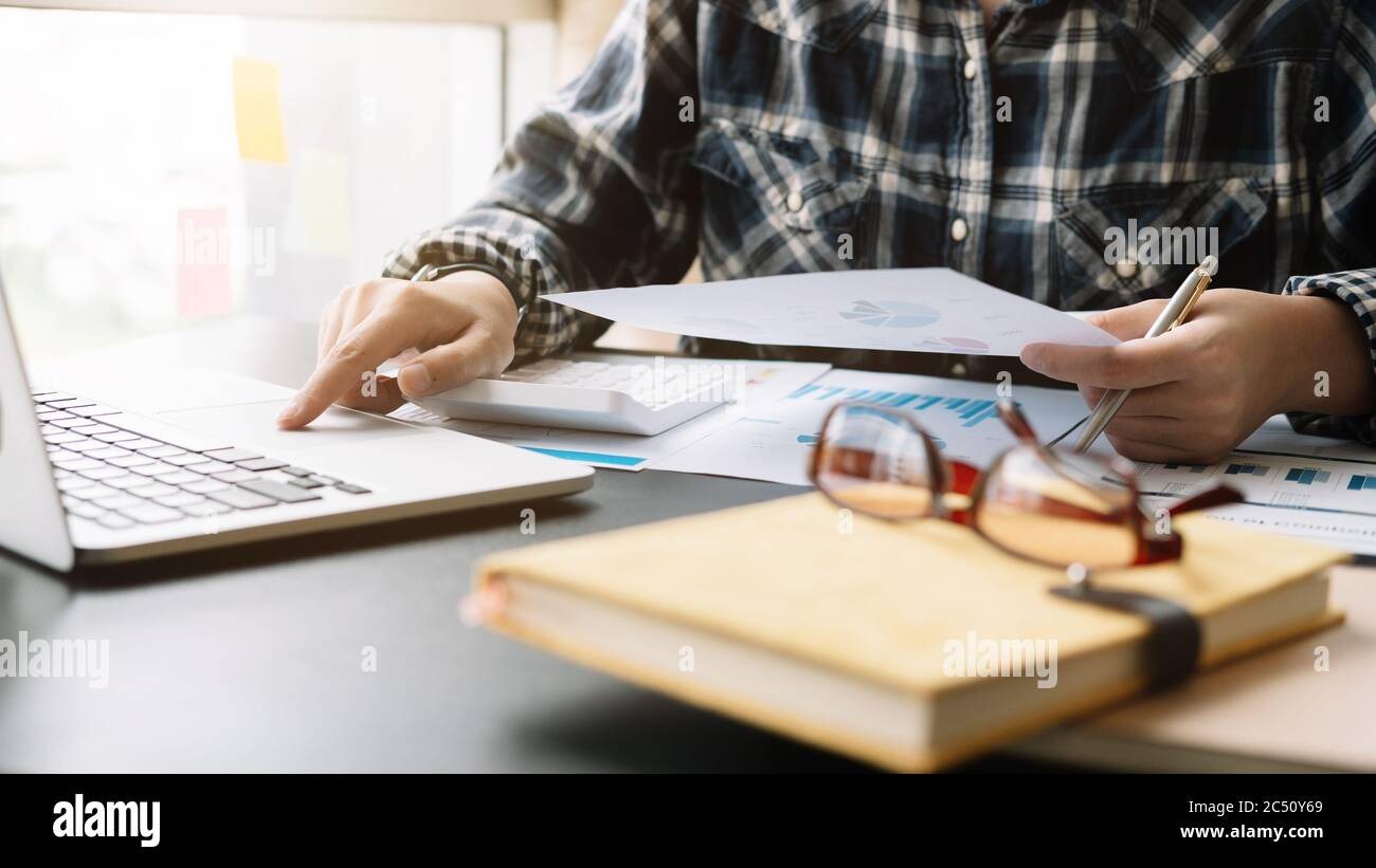 Close up Businessman using calculator and laptop for calculating finance, tax, accounting, statistics and analytic research concept Stock Photo