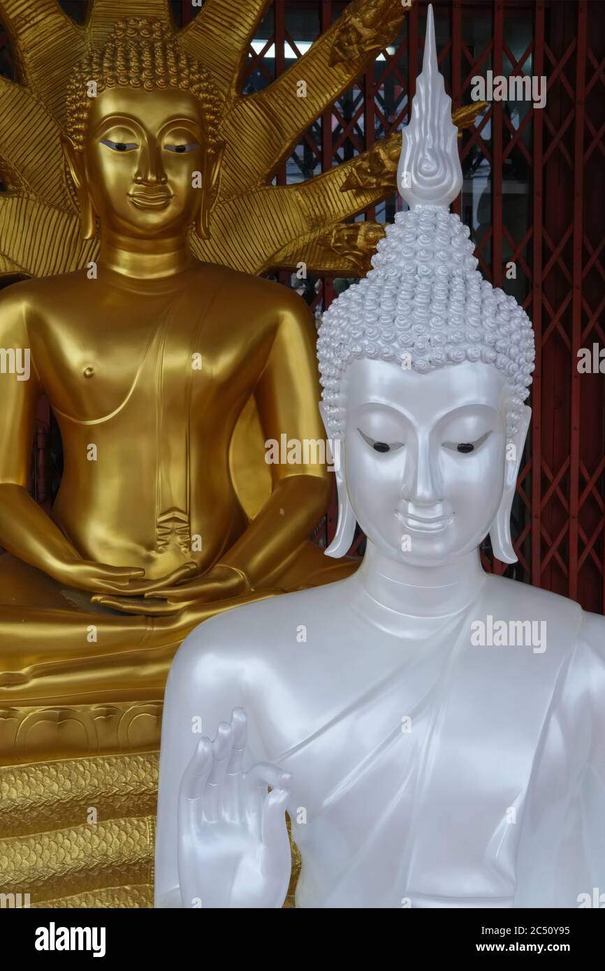 A white Buddha, yet unfinished, in front of a finished golden Buddha at a factory outlet for religious objects; Bamrung Muang Road, Bangkok, Thailand Stock Photo
