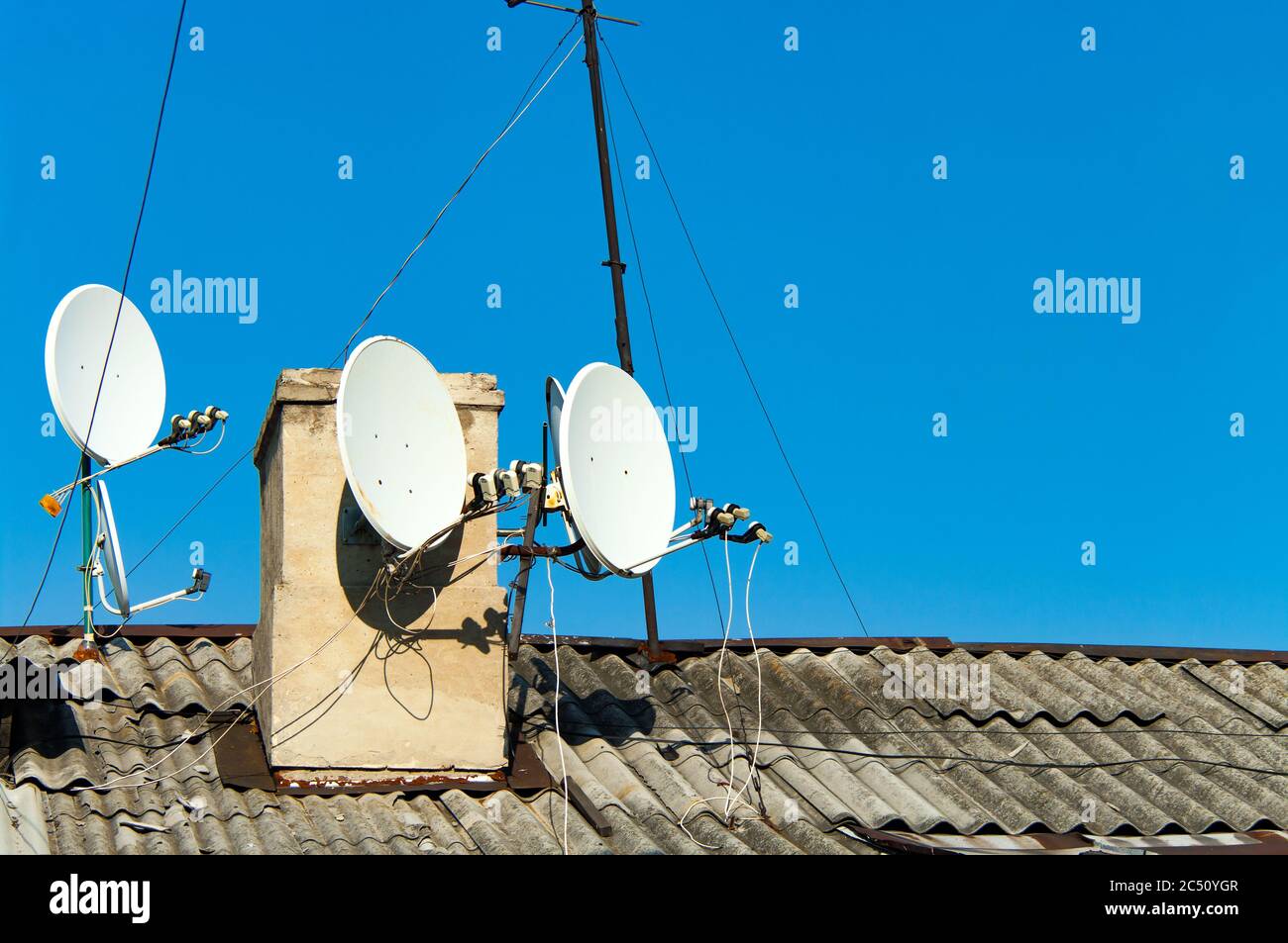 Satellite dishes on the old roof against the blue sky Stock Photo
