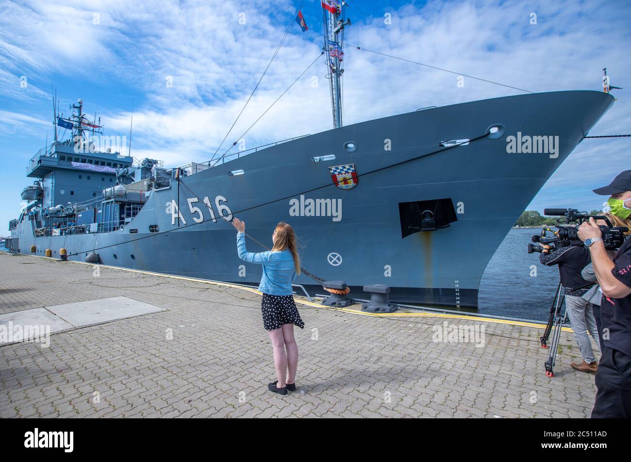 25 June 2020, Mecklenburg-Western Pomerania, Warnemünde: Claudia Scheller is waiting in front of the naval tender 'Donau' for her 29-year-old friend, Obermaat Diehr. The navy soldier had proposed marriage with a large banner on the bridge of the supply ship when the ship entered. Due to Corona, the supply ship could not call at any ports for the last 102 days and the 70 or so soldiers had to stay on board. In addition to the 'Danube', up to ten mine-defence units from Nato member states belonged to the unit. Photo: Jens Büttner/dpa-Zentralbild/ZB Stock Photo