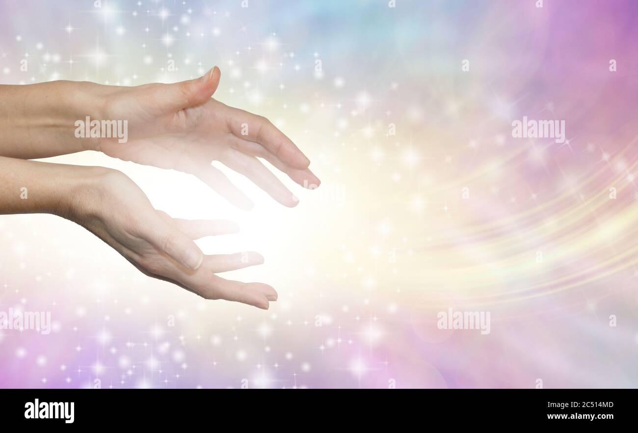 I am sharing pure healing energy with you - female healer sending out beautiful angelic energy against pale pink yellow blue background and copy space Stock Photo