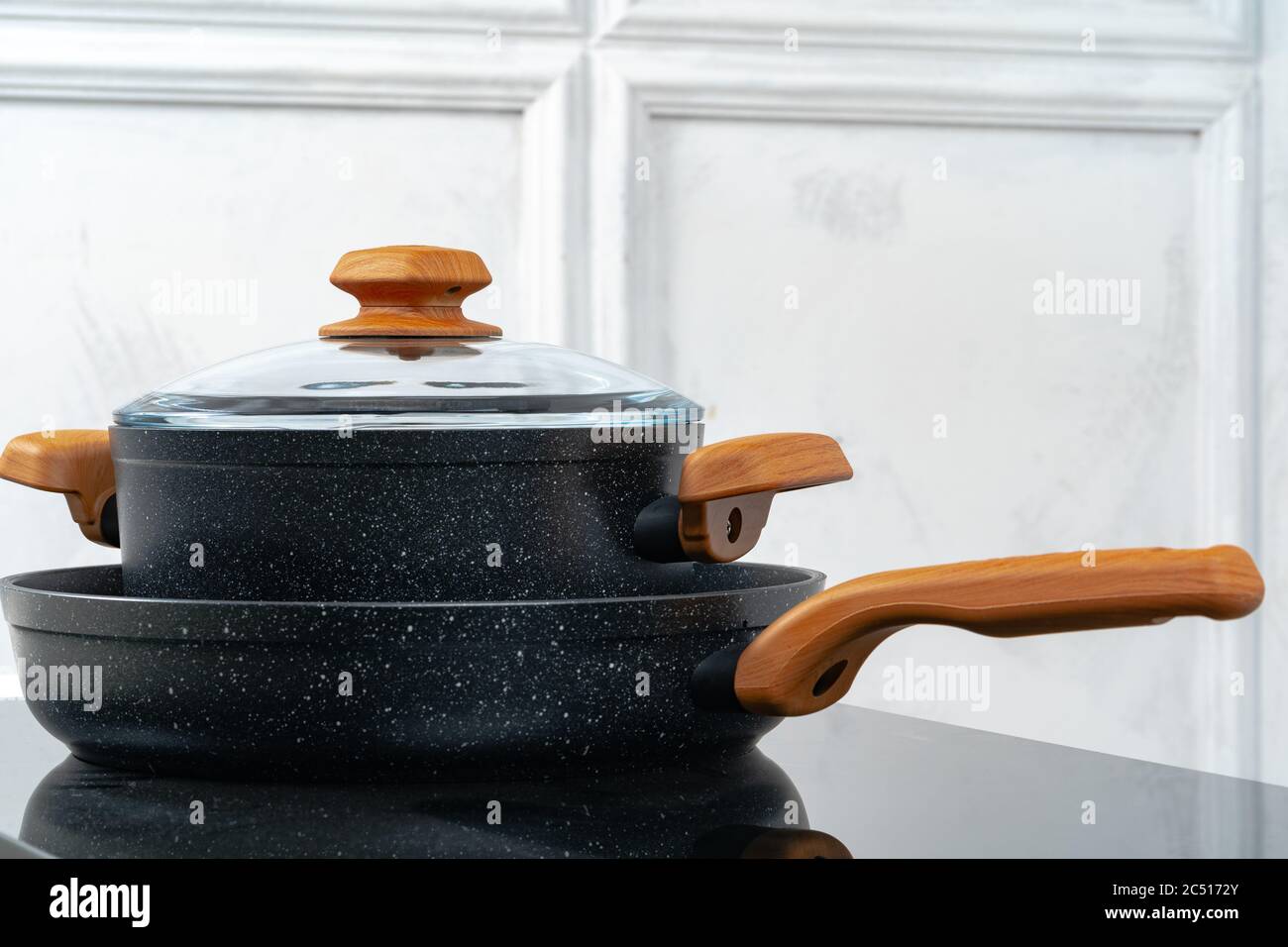Black cookware on induction stove against grey wall Stock Photo Alamy
