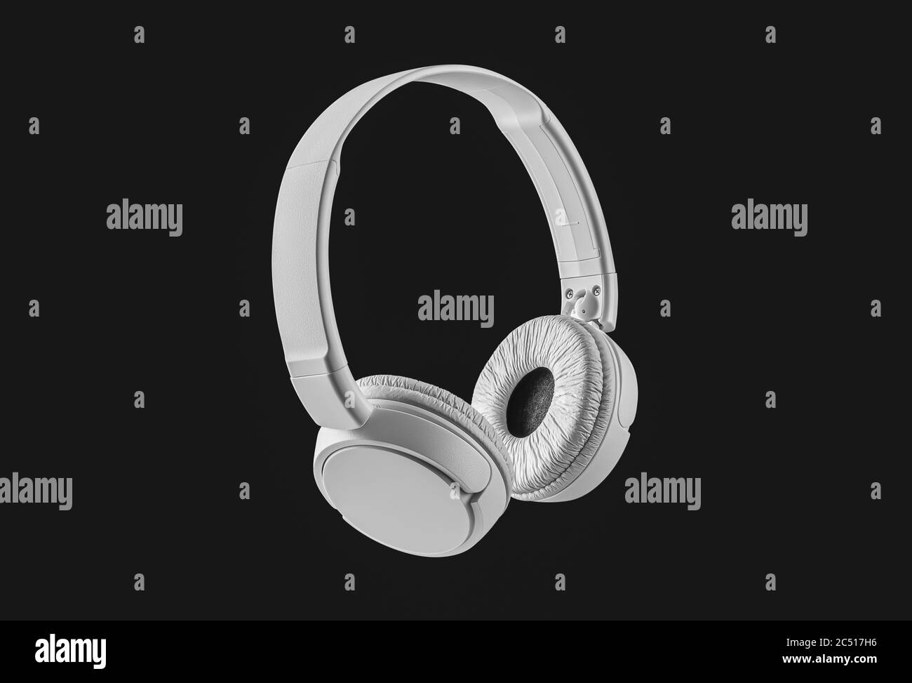 Modern white wireless headphones on a black background. Earphones with copy space and clipping path. Design element. Stock Photo