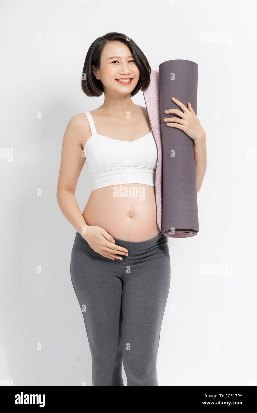 Positive pregnant woman in sports clothes holds a gym Mat in her hands. Stock Photo