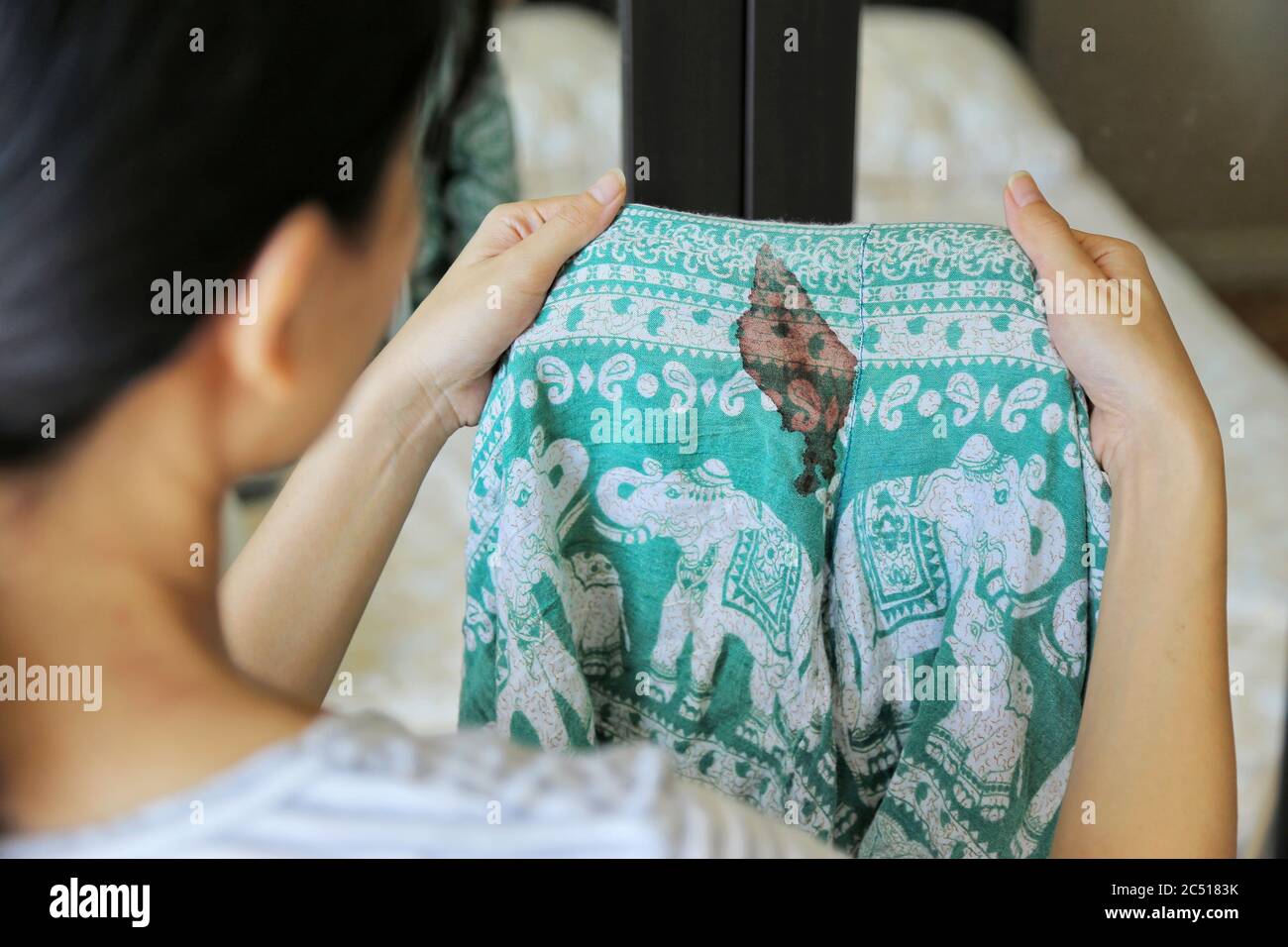 Women hold short pants with period blood spot stains on blur background.  Need to be cleaned Stock Photo - Alamy