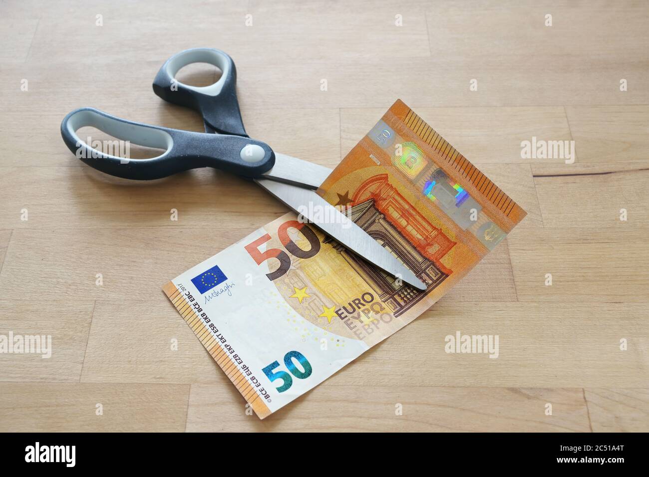 Euro banknote is cut with scissors, business concept for German lower MwSt (value added tax), wage reduction and pay less money during coronavirus pan Stock Photo