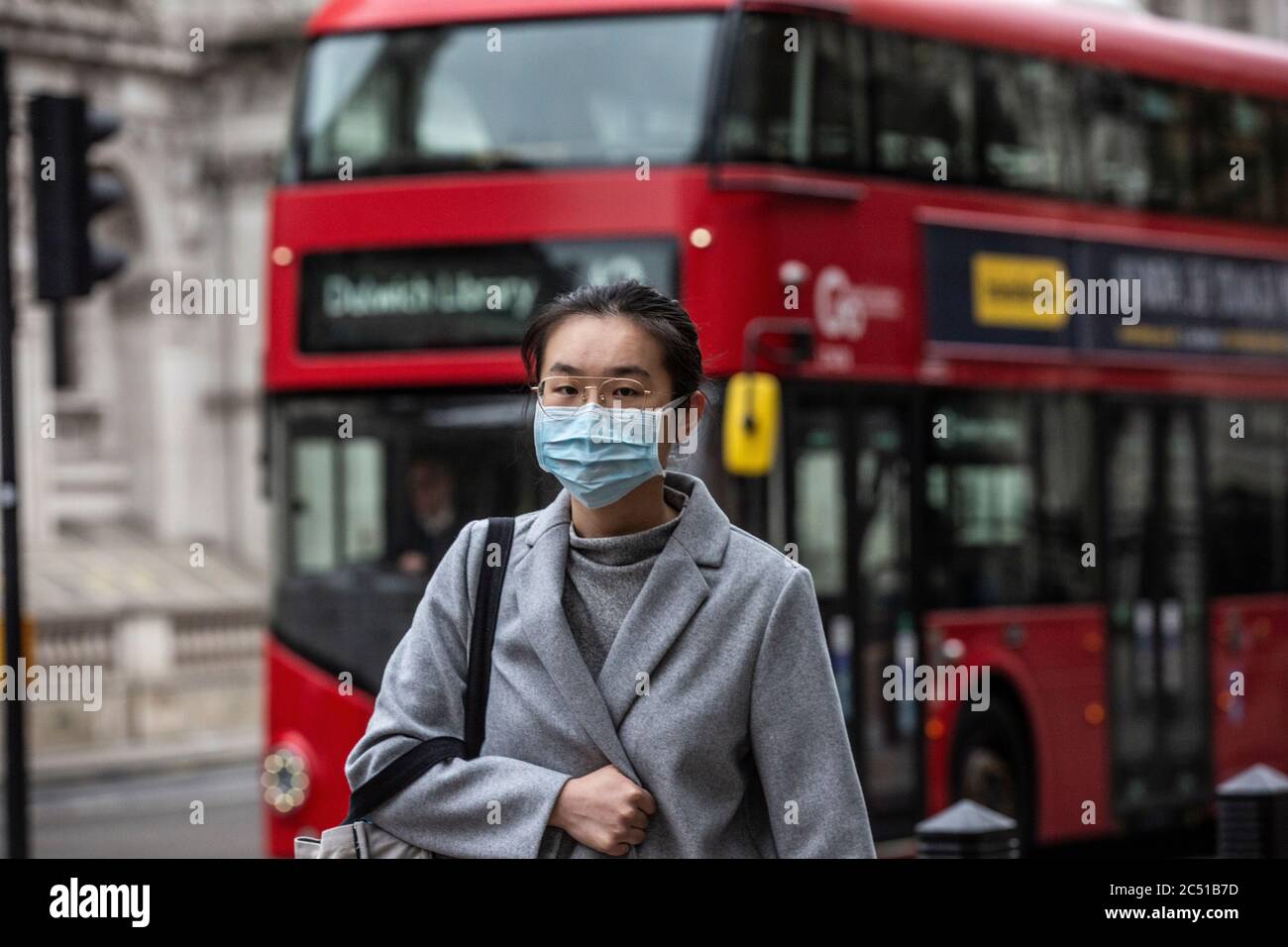 Pedestrian asian woman walks along Oxford Street wearing a face mask during the early stages of the coronavirus Covid 19 pandemic, London, UK Stock Photo