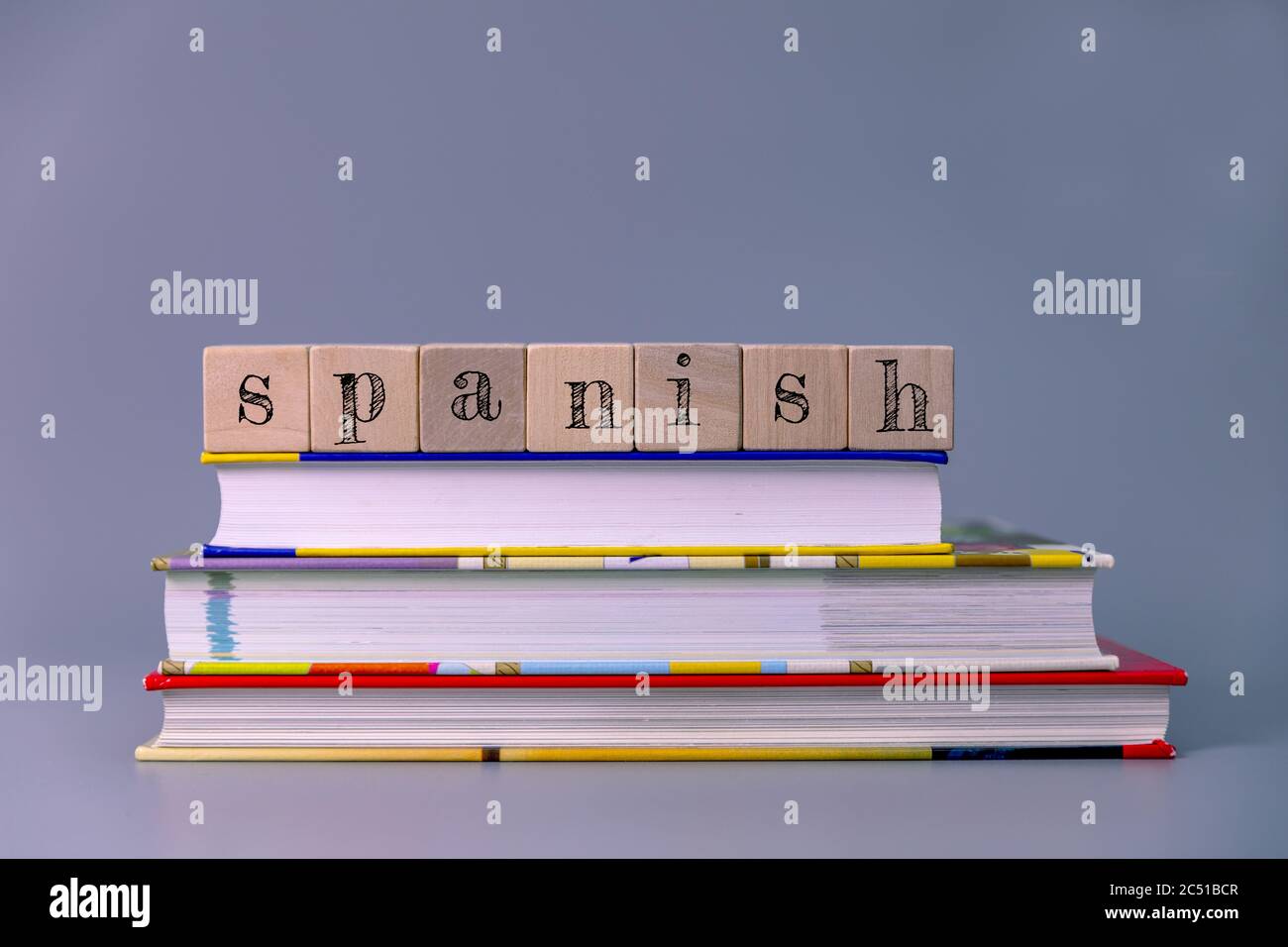 spanish language course and learning concept. stack of books with wooden blocks Stock Photo