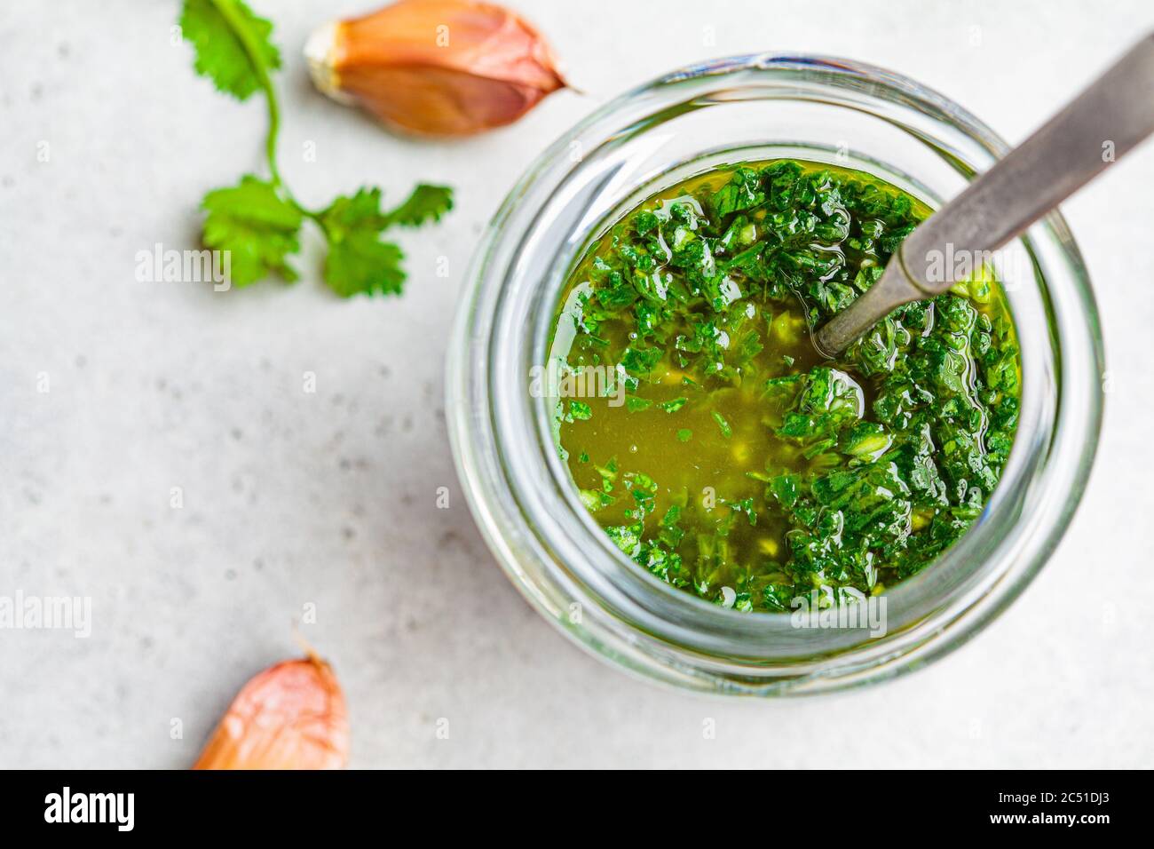 Fresh traditional chimichurri sauce for barbecue meat in a glass jar, light background. Stock Photo