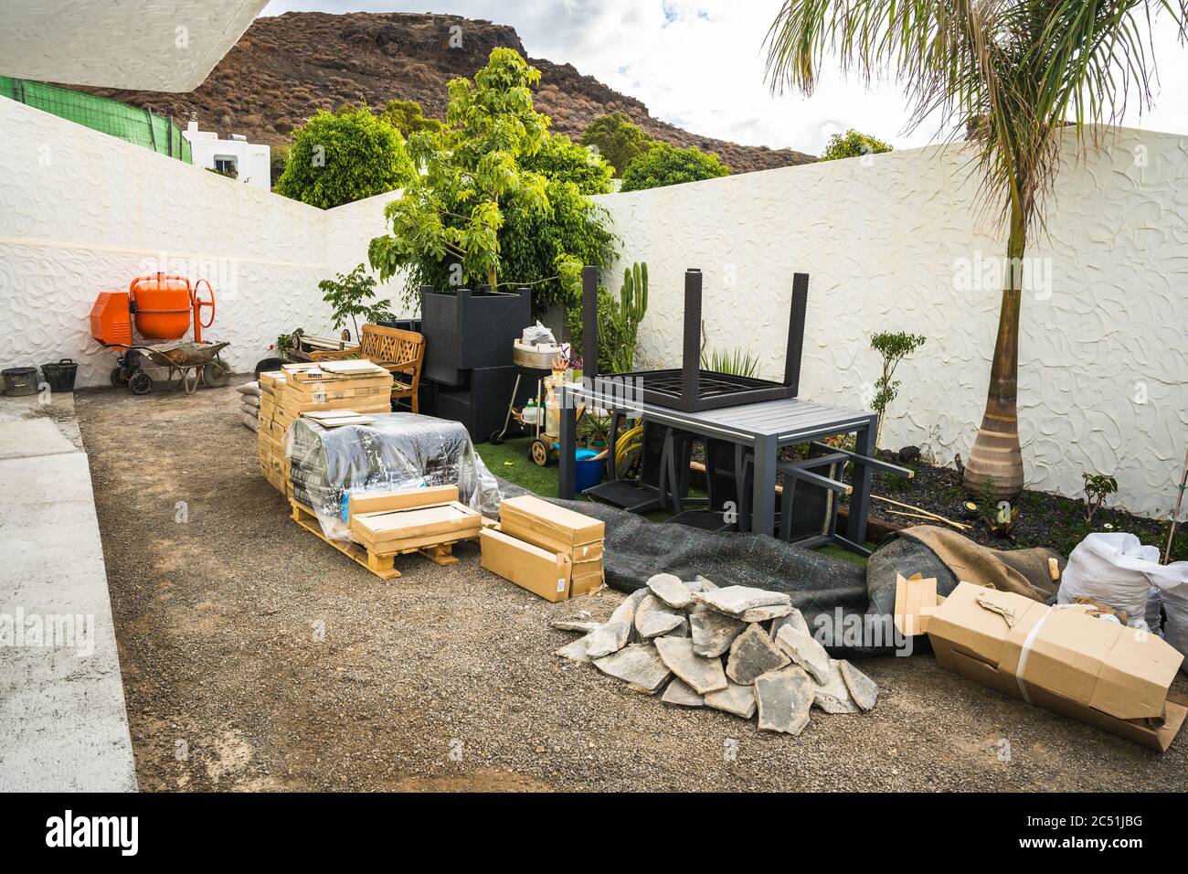 Scattered construction site materials and tools in backyard. Construction work beginning early stage ready for garden backyard renovation Stock Photo