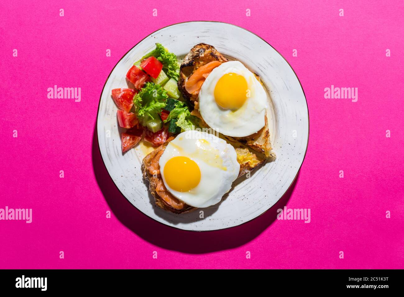 Fried eggs from two eggs on a pink background Stock Photo