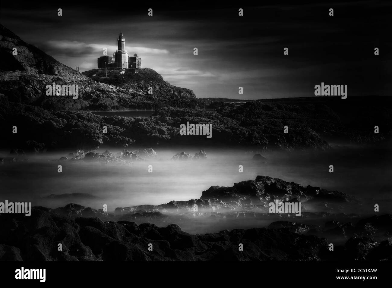 The Mumbles with it's lighthouse as seen from Bracelet Bay on the Gower Peninsular Wales, UK black & white monochrome image Stock Photo
