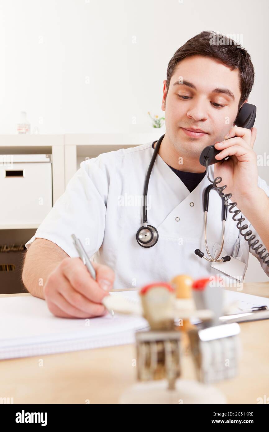 Doctor making phone calls in the practice takes notes Stock Photo