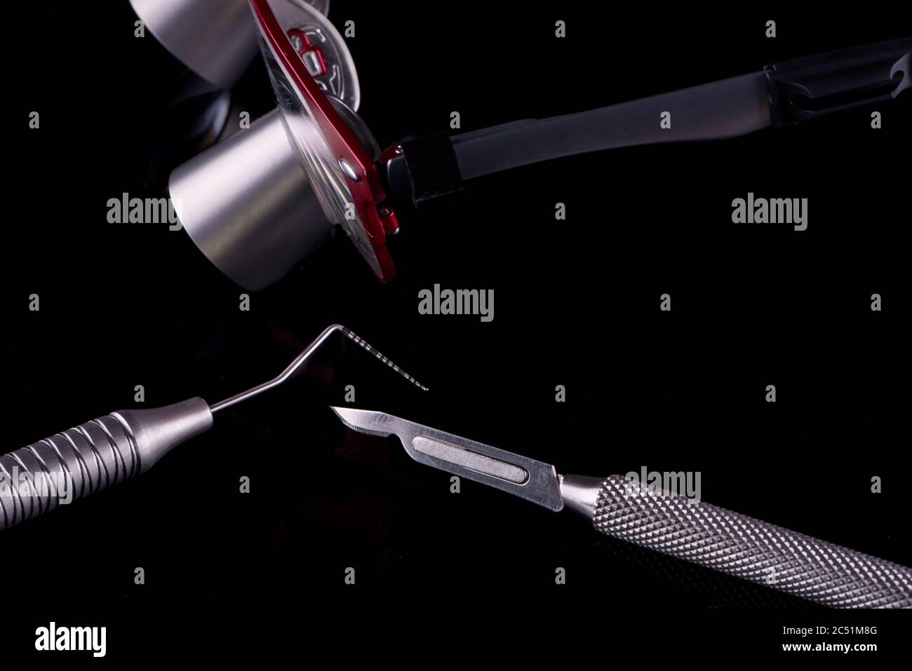 Horizontal color image with a front view of a professional dental tools on a black background Periodontal probe, scalpel and magnifying glasses. Stock Photo