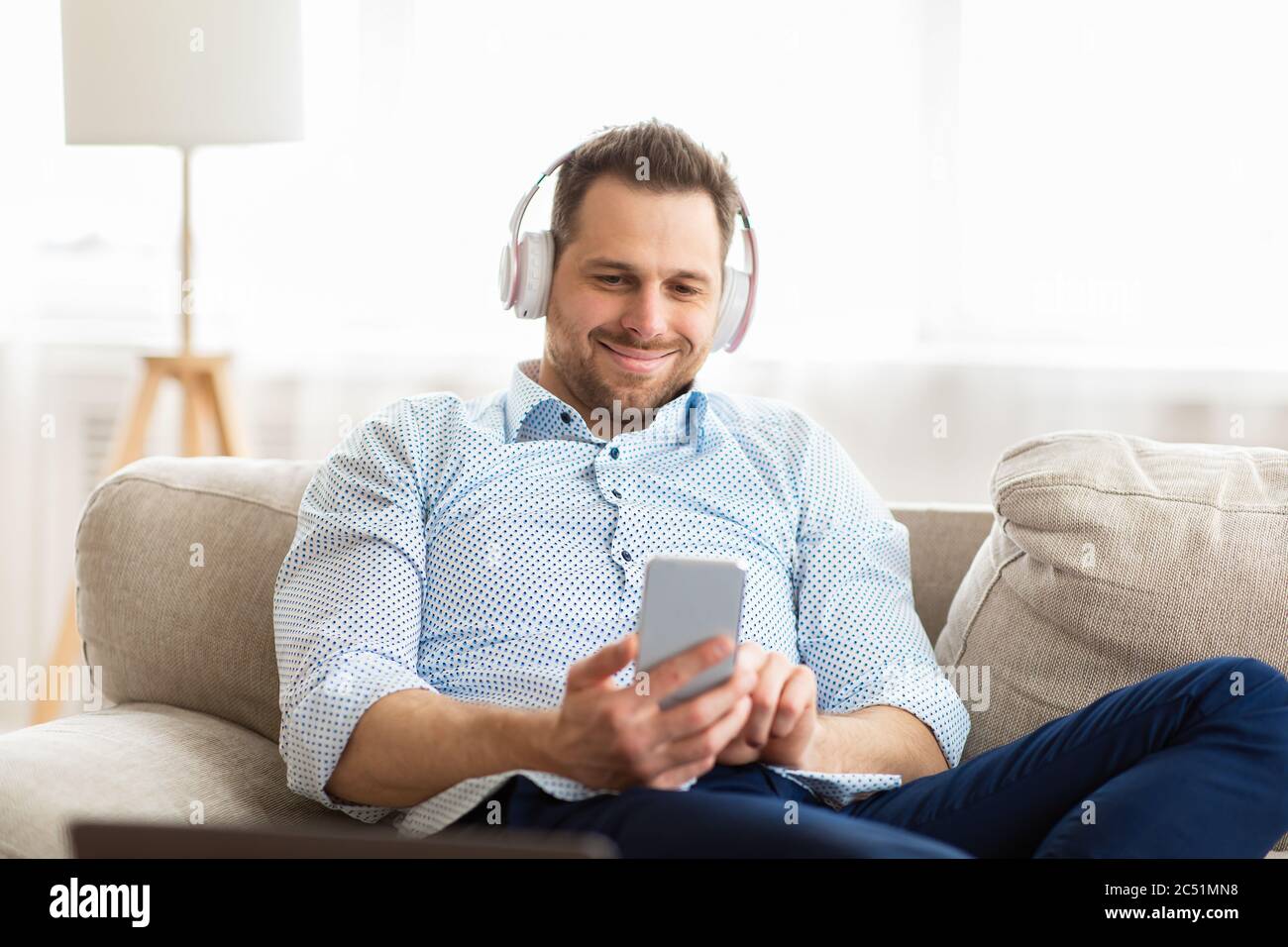 Happy man listening to music sitting on couch Stock Photo - Alamy
