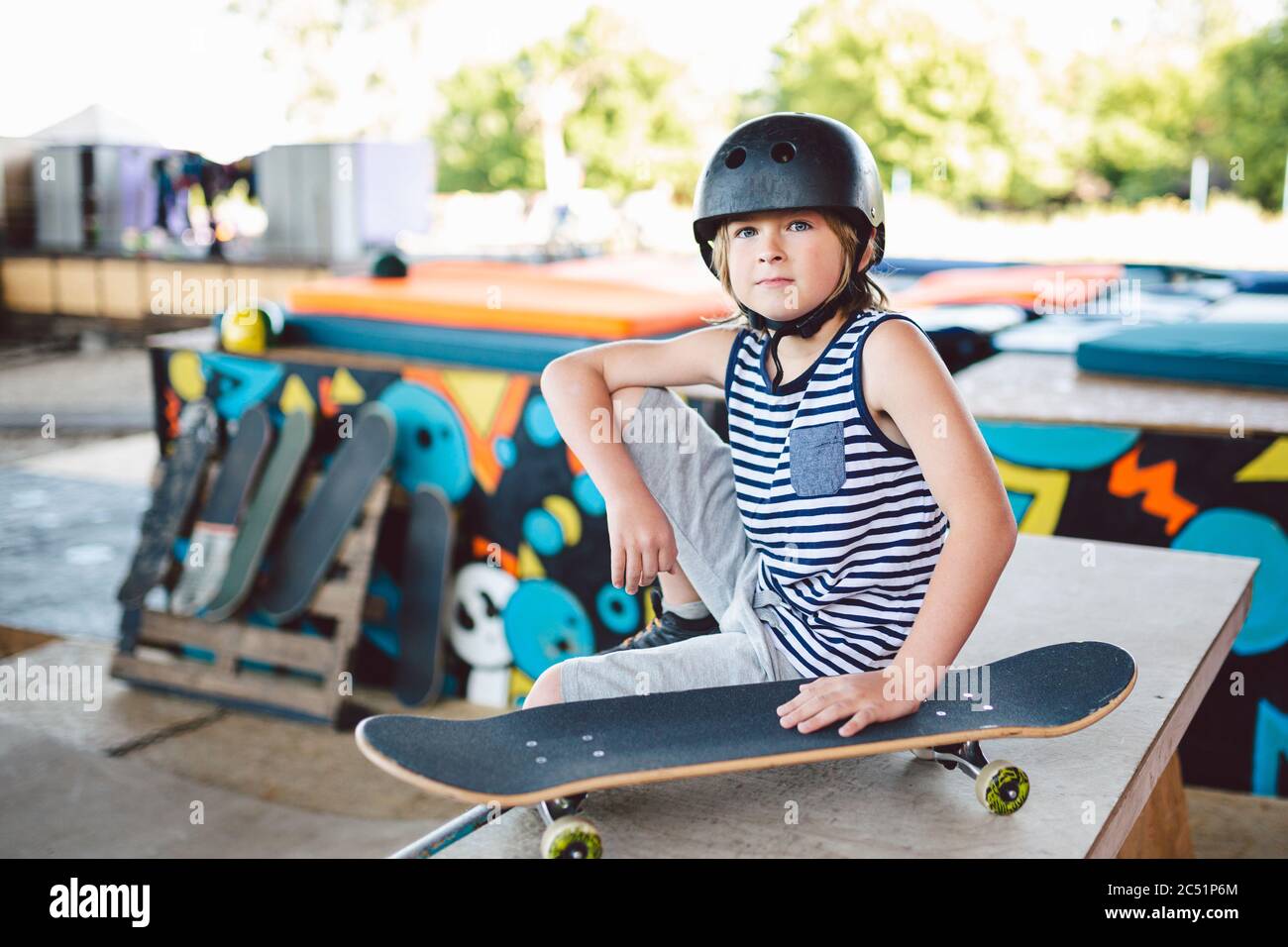 Boy sitting at skatepark, looking camera. Kid resting with skate board ...