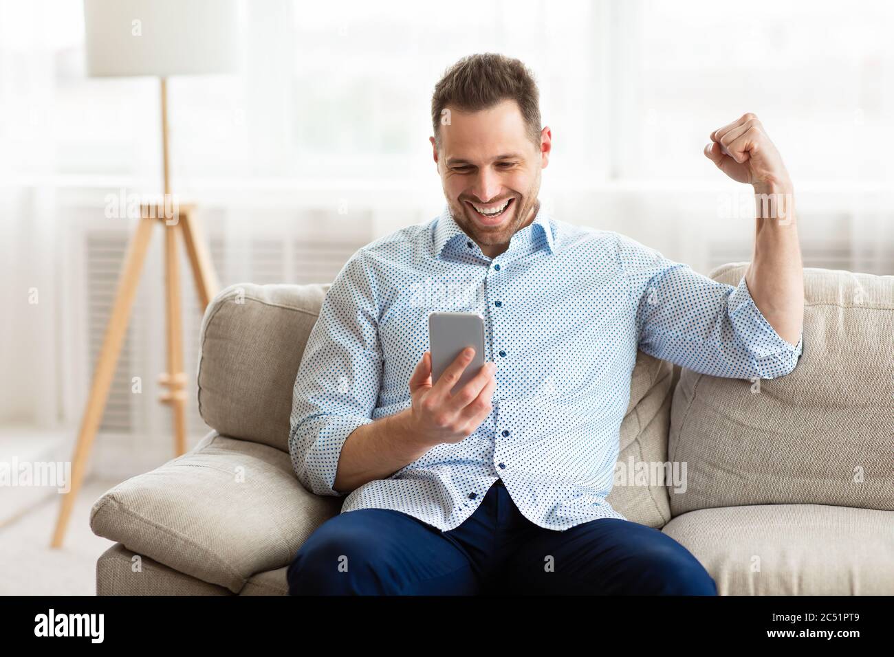 Excited adult man feeling ecstatic holding phone Stock Photo
