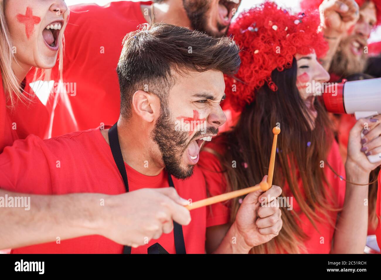 Red sport fans screaming while supporting their team out of the stadium - Football supporters having fun at competion event - Champions and winning co Stock Photo