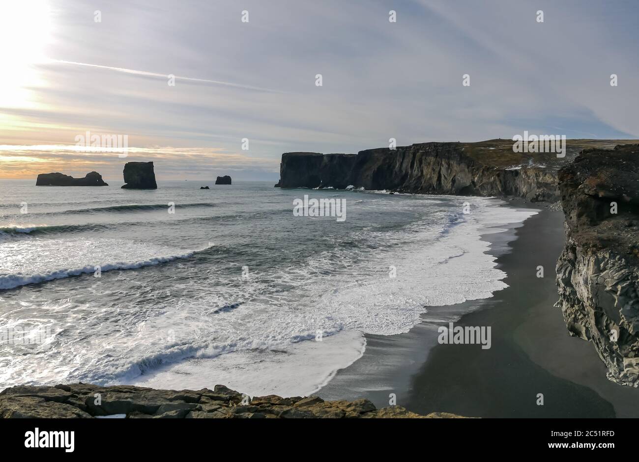 View from clifftop at Dyrhólaey overlooking black lava beach and sea stacks at dusk in Winter, Iceland Stock Photo