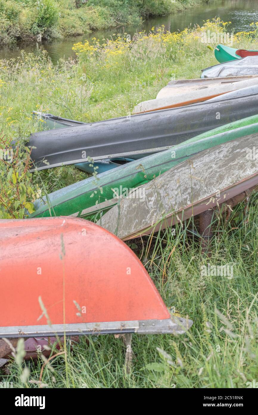 Group of upturned canoes and kayaks at kayak launch site on the River Fowey at Lostwithiel, Cornwall. For messing about on the river, river sports Stock Photo