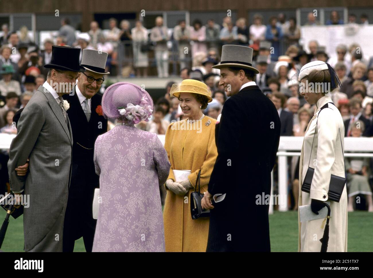 Queen Elizabeth 1980s UK. Queen Mother, Princess Ann and courtiers the Derby Day horse racing Epsom Downs. Lord Porchester the Earl Carnarvon half back view in black tail coat. Circa 1985 HOMER SYKES Stock Photo