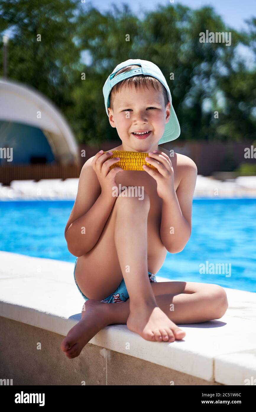 boy on the beach eating corn on the beach Stock Photo