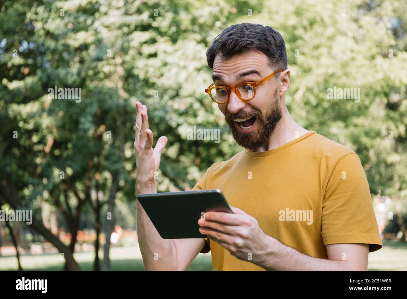 Emotional man using digital tablet, shopping online, watching movie. Excited guy looking at screen, celebration success, sport betting concept Stock Photo