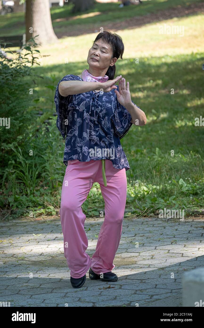 An Asian American woman dances vigorously to Chinese music for over 30 minutes. In Kissena Park, Flushing, New York City. Stock Photo