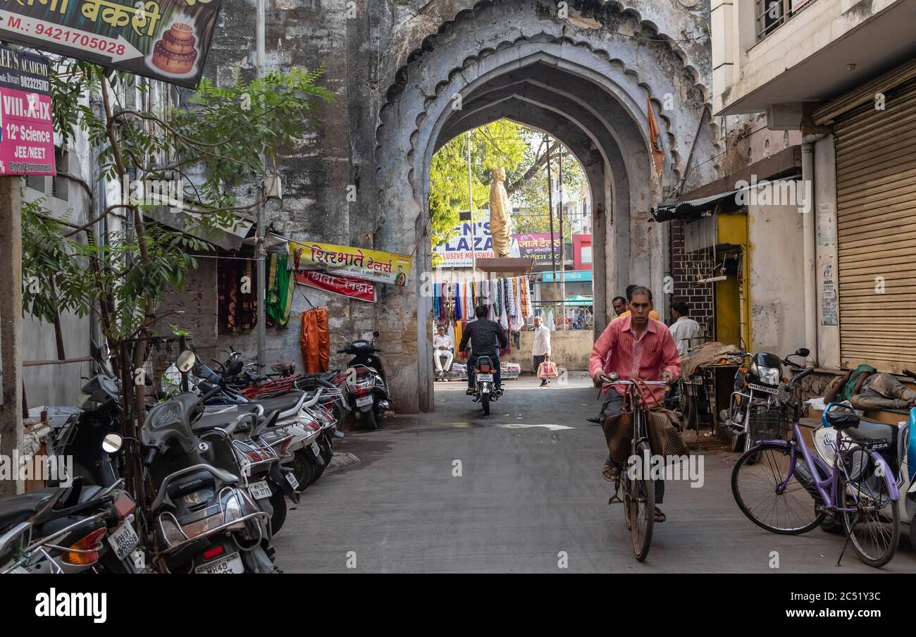 Nagpur, Maharashtra, India - March 2019: A man on a bicycle rides with an ancient arched gateway in the background in the old city of Nagpur. Stock Photo