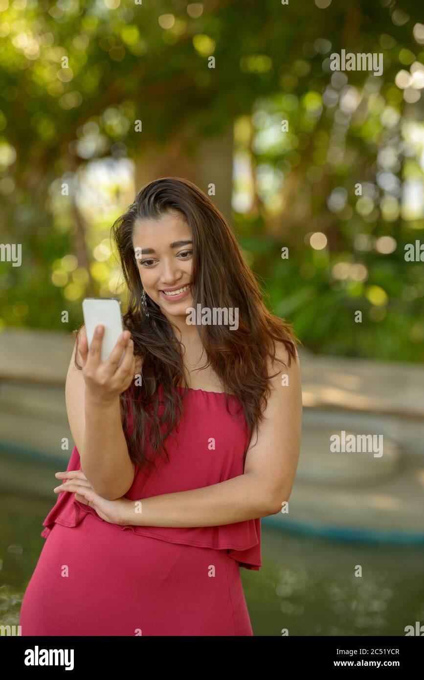Happy young beautiful Indian woman using phone at the park Stock Photo ...