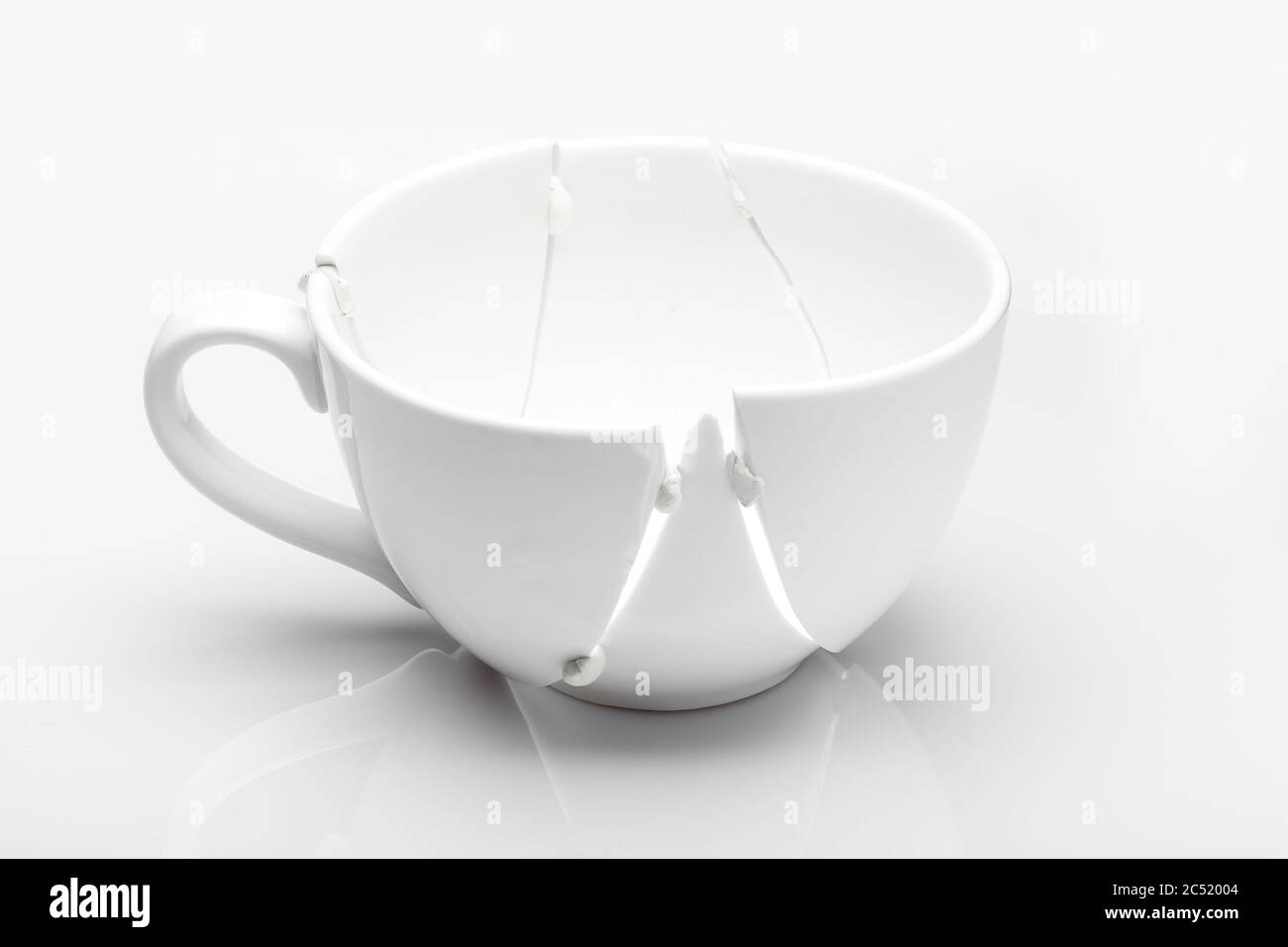 white ceramic cup broken into fragments as a result of the fall and ...