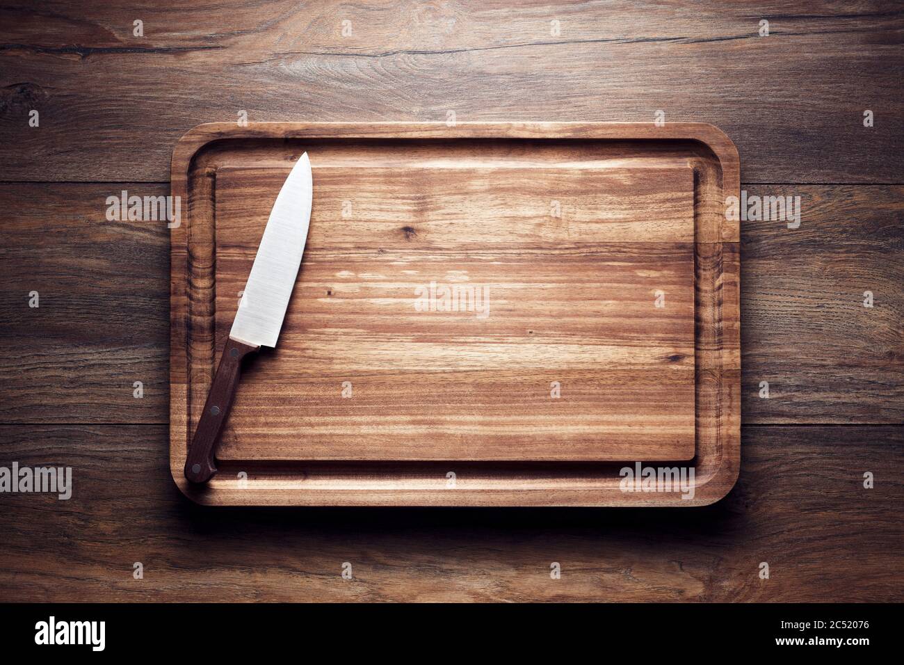 Empty vintage wooden cutting board with knife on wooden table. Overhead view with copy space. Stock Photo