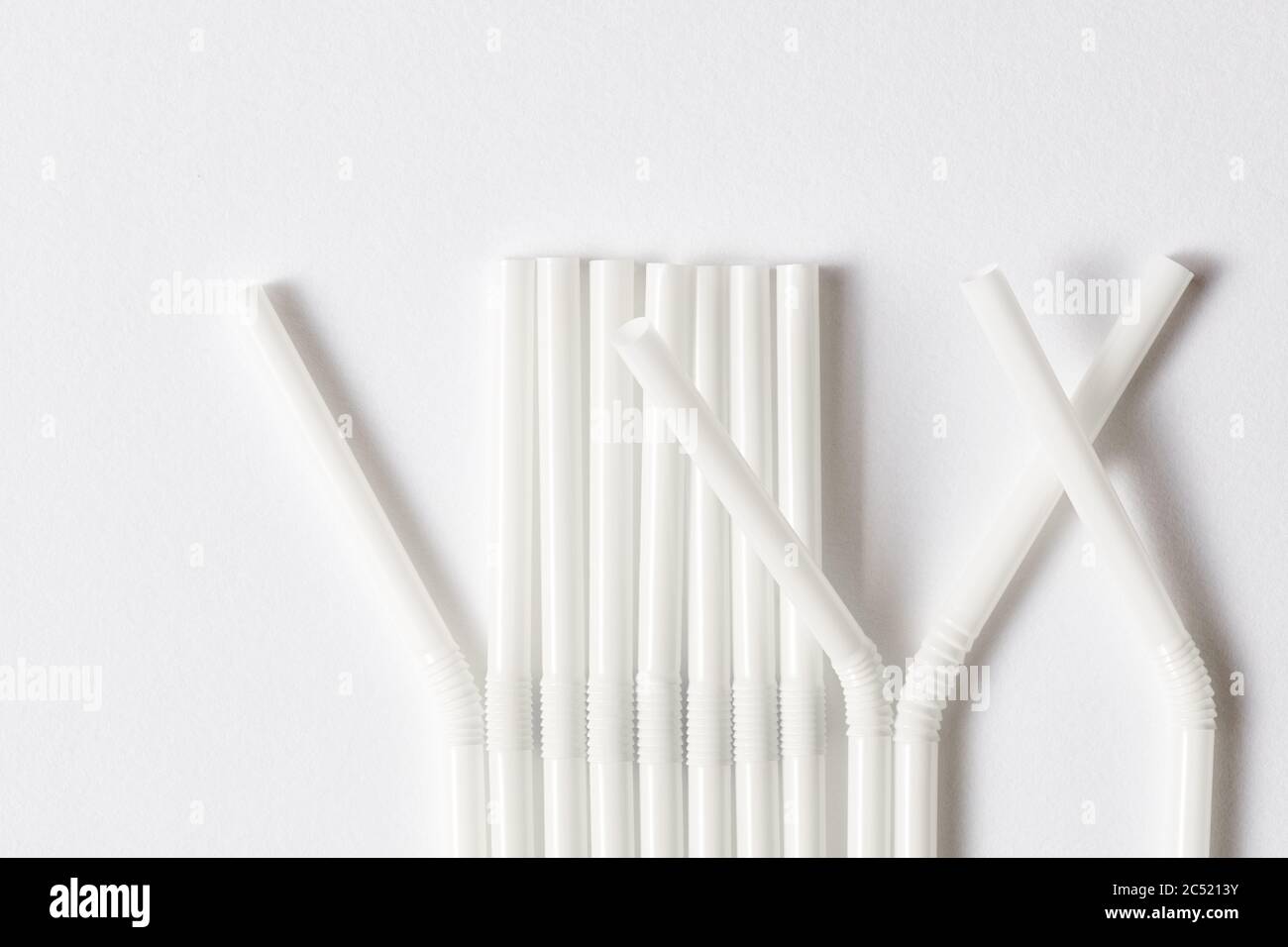 Row of white flexible plastic straws for beverages on white background. Stock Photo