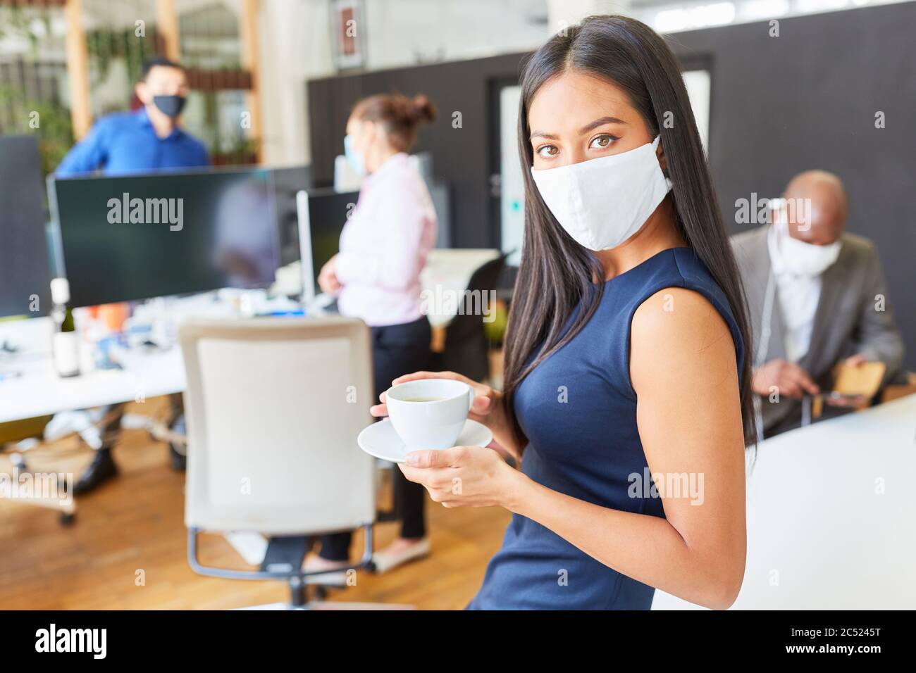 Business woman with coffee cup and face mask in the office as a ...