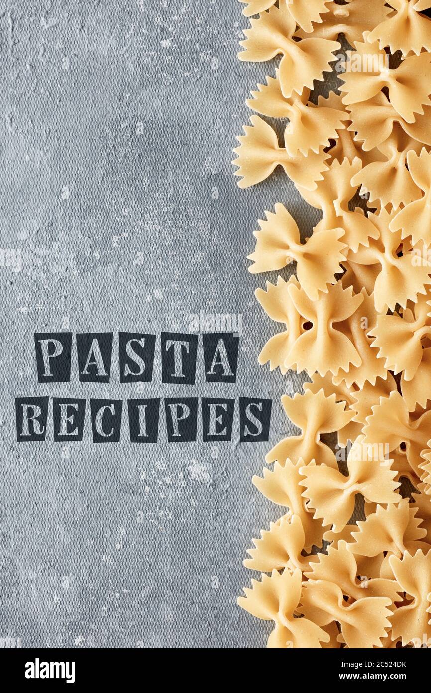 Template for pasta recipe with raw farfalle on textured gray background. Overhead view. Stock Photo