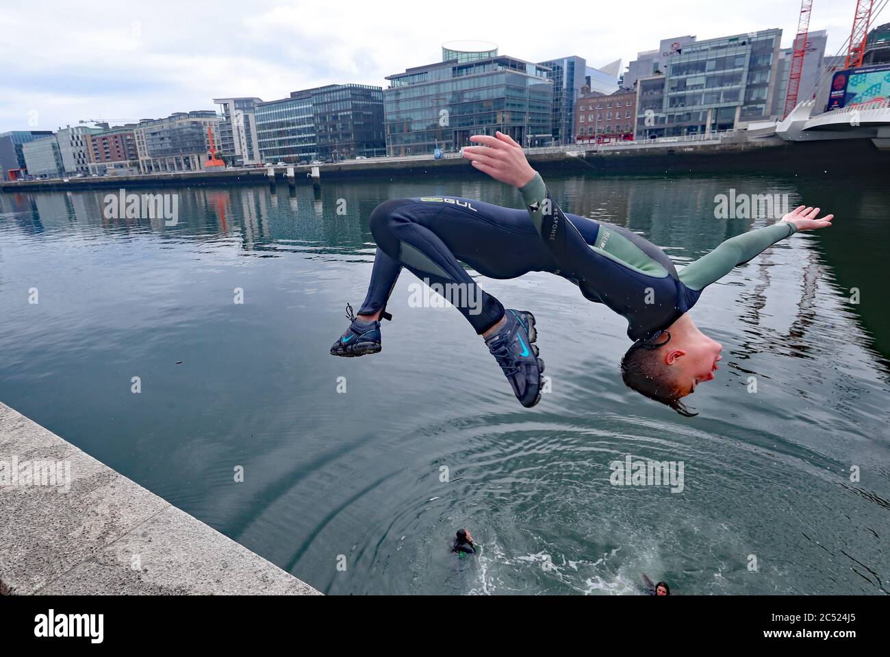 Evan Burke jumps into the river Liffey in Dublin, as rain, wind and weather warnings are bringing an end to the sweltering June heatwave. Stock Photo