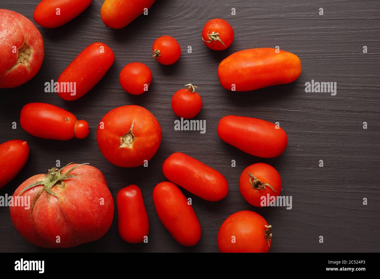 Organic long tomatoes on black background Stock Photo
