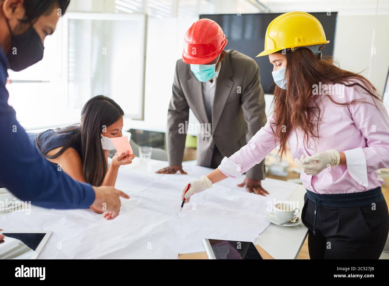Business people and architects with a mask because of Covid-19 discuss a construction project together Stock Photo