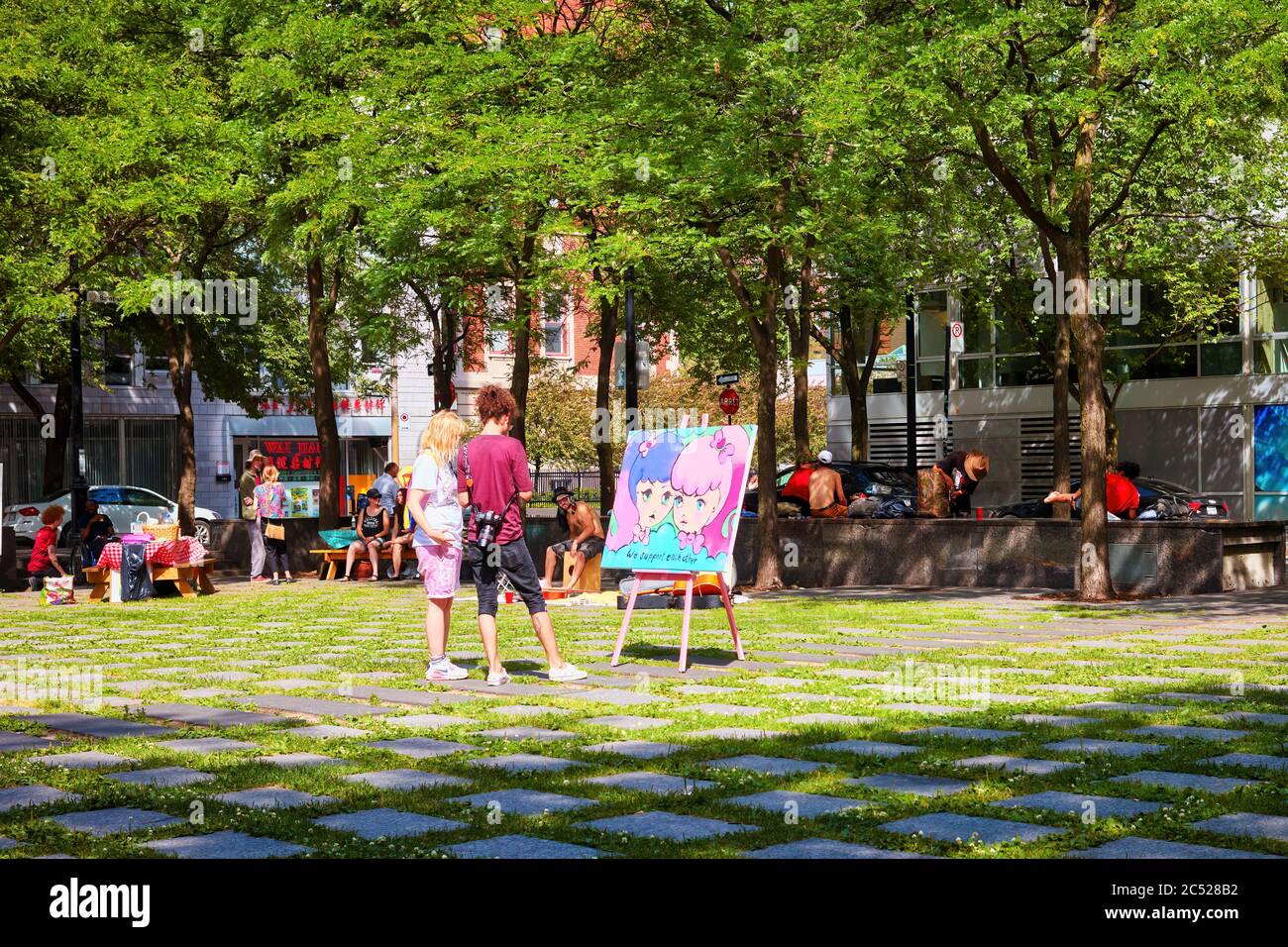 Montreal, Canada - June, 2018: Young Canadian couple looking at a painting in peace park or place de la paix in Montreal, Quebec, Canada. Stock Photo