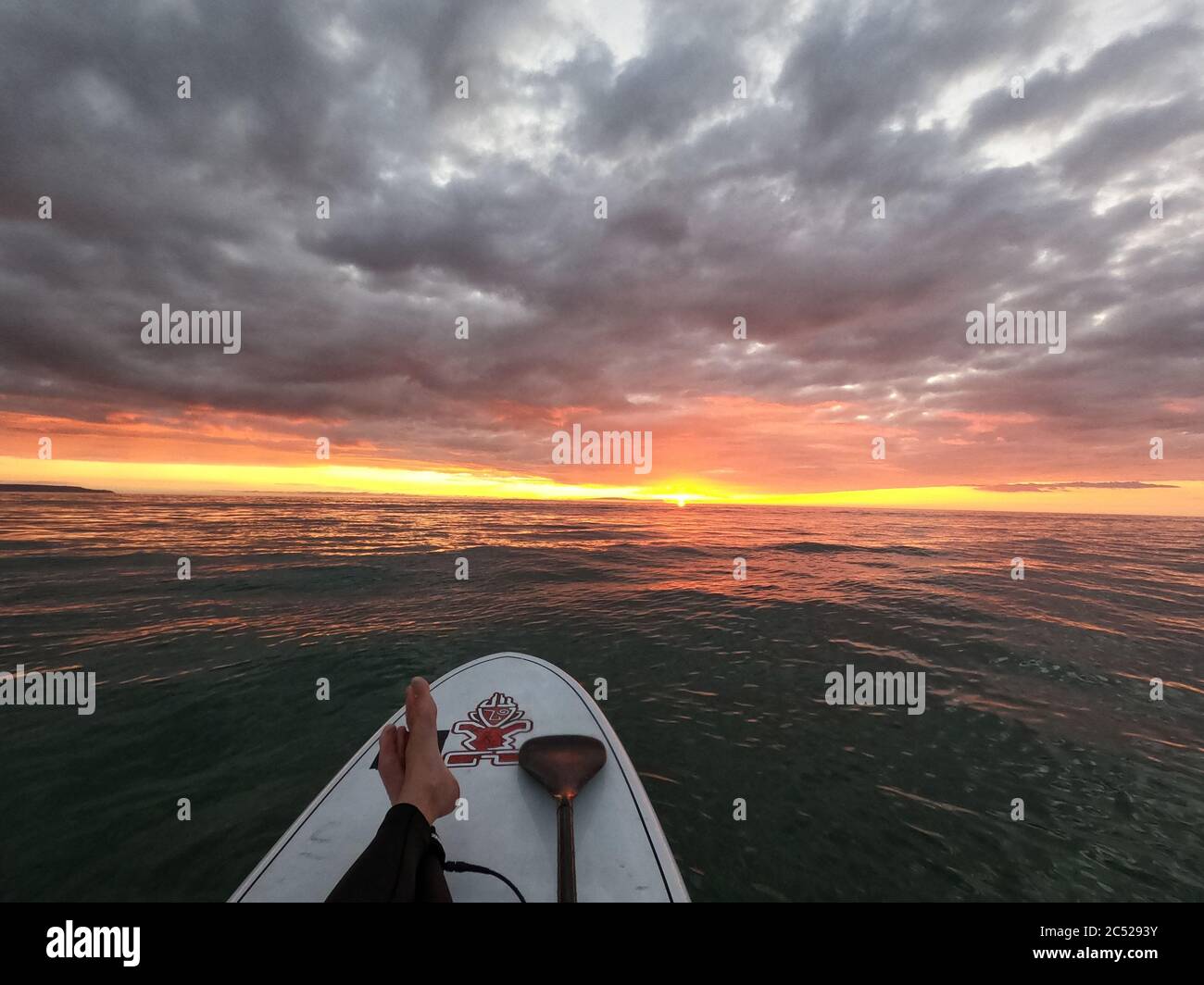 Escaping the virus. Watching an Incredible sunset on a Stand Up paddle board during coronavirus lockdown Stock Photo