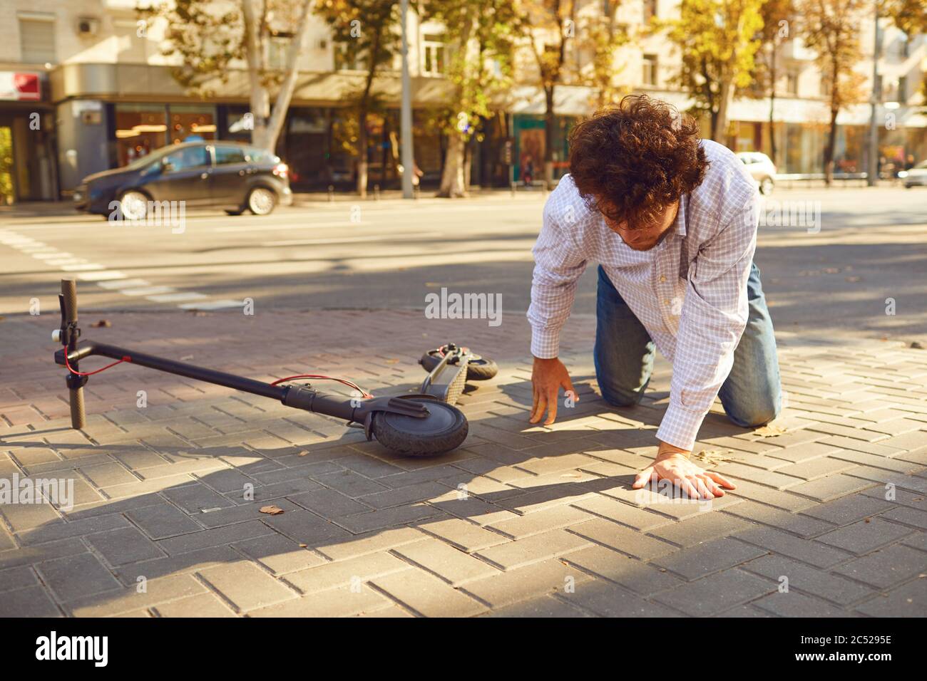 Accident with an electric scooter. A man fell from a scooter on a city street. Stock Photo